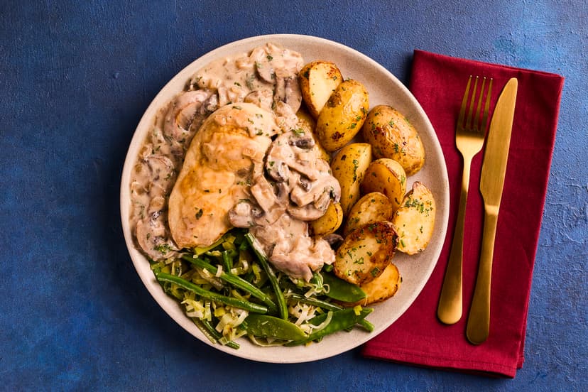 Chicken and mushrooms are a match made in heaven! In this deliciously savoury dish, roast chicken breasts are smothered in a creamy mushroom and yogurt sauce, served with garlicky roast potatoes and a medley of green veg.