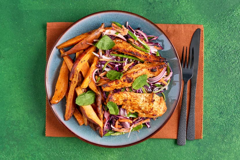 This is a feast for the eyes as well as the taste buds! Tender strips of chicken breast, marinated in Thai red curry paste, are served with golden sweet potato wedges and a crunchy cabbage, carrot and mangetout slaw in a zippy dressing of yogurt, mint, coriander, lime and tamari.