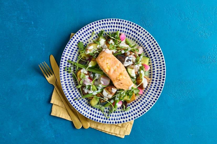 Put the zing into spring with this stunning salmon supper! Baby potatoes and onions are roasted with succulent salmon fillets – zinged up with lemon zest – and served with green beens, courgette and radish. A kick of horseradish in the lemony sauce and a sprinkle of pea shoots seal the deal.