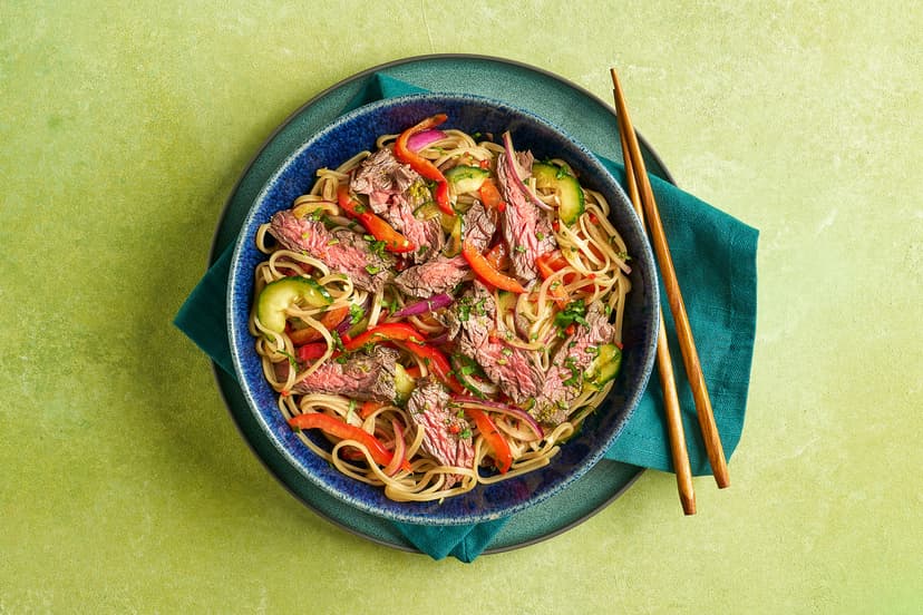 Bright, bold, and packed with flavour, this Thai-inspired steak salad is a real midweek hero. Tender strips of sizzled bavette are piled over nutty brown noodles, crisp cucumber, red pepper and onion, all tossed in a punchy Thai dressing. Crown it with coriander and dive in!